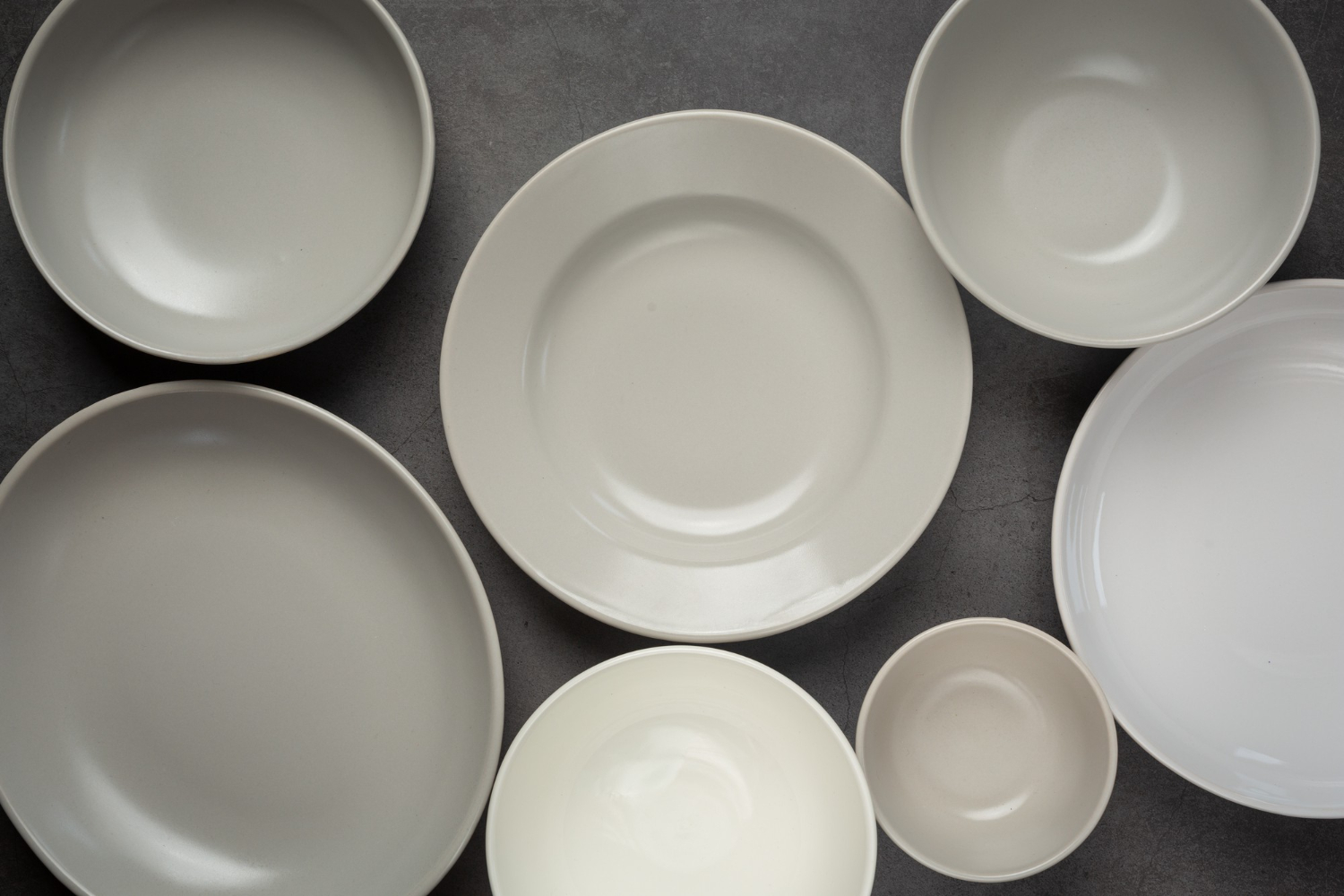 white-round-empty-plates-bowls-dark-surface